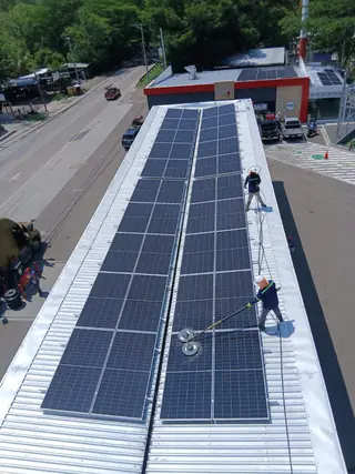 Técnicos lavando paneles solares sobre un techo
