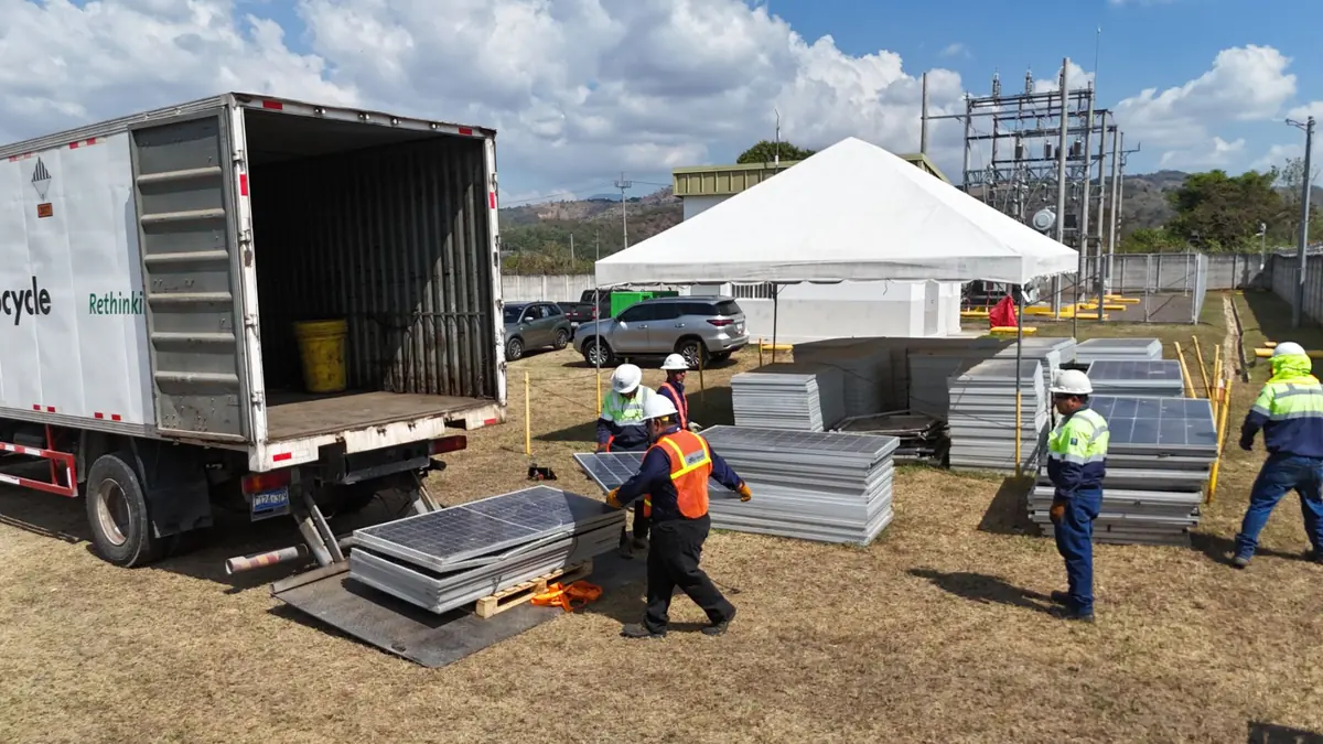 Cuadrilla retirando paneles solares usados junto a un camión de reciclaje